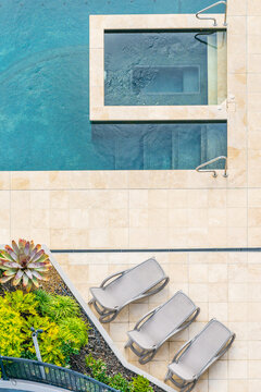 Aerial view of paving around a pool and spa with deck chairs and gardens