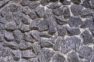 Fragment of a stone wall on a summer day close-up