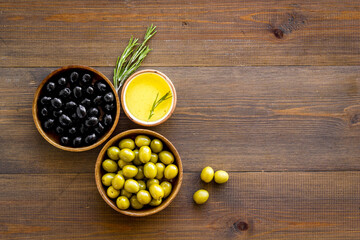Top view of green and black olives in bowls with oil