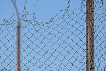 A fragment of a mesh fence against a blue sky