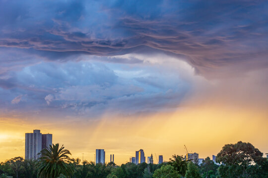 Dark cloud formations over a city skyline at sunset