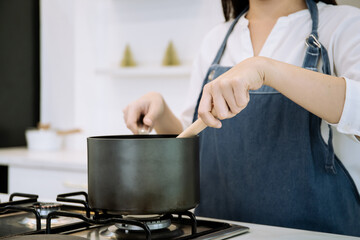 Unrecognizable Cheerful Asian woman cooking in the modern kitchen.
