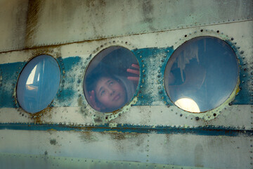 A young man on board an old abandoned Soviet plane. The guy looks out the window.