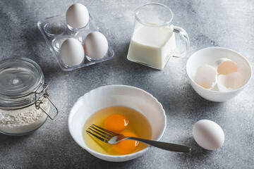 Raw ingredients for making an omelet. Eggs and flour on a gray background. Cooking concept.