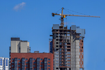 Fototapeta na wymiar Construction crane near a residential building under construction on a summer day