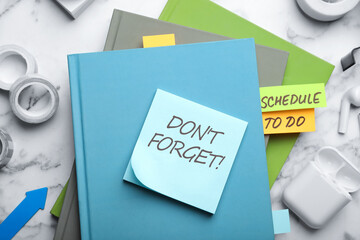 Reminder note with text DON'T FORGET and stationery on white marble table, flat lay