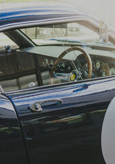 Lujoso coche clásico de color azul. Detalle del volante desde la puerta del conductor.