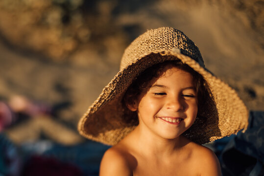 Happy kid in hat enjoying summer holidays on beach