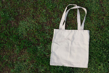 White cotton or mesh eco bag on green grass background. Zero waste, no plastic, eco friendly...