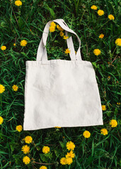 White cotton or mesh bag on dandelion grass background. Zero waste, no plastic, eco friendly...