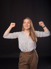 Portrait of a happy woman celebrating success isolated over black background.