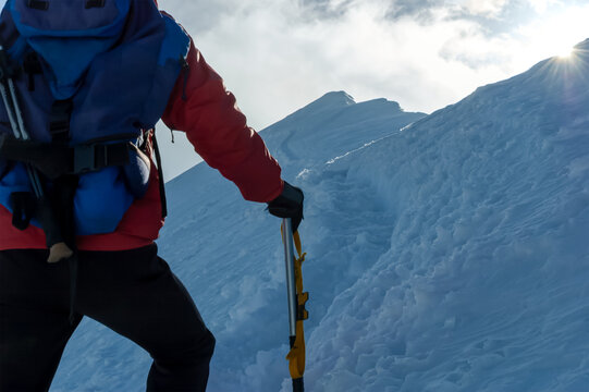 Mountaineer climbing a snowy ridge at sunrise.