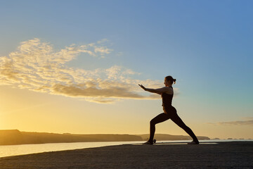 Fototapeta na wymiar silhouette of Caucasian woman making a posture of the yoga warrior