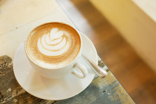 a cup of late coffee with flower shape design on top at cafe 