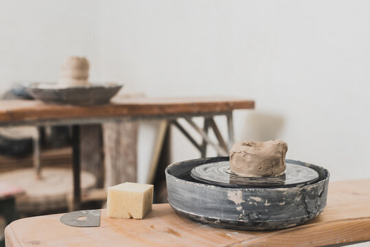 wet piece of clay on pottery wheel and sponge on wooden bench in art studio