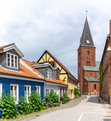 neighborhood street in historic Aalborg city center with colorful houses and the Church of Our Lady in the background