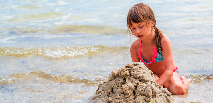 Beautiful young girl playing on sea beach. Summer holiday, rest and vacation concept. Horizontal image.