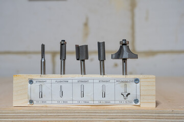 Set of five quarter inch hardened steel woodworkers router bits with description and sizes set in a piece of wooden board