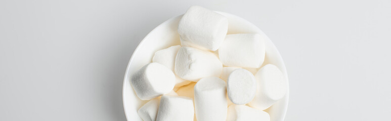 top view of soft and puffy marshmallows in bowl on white, banner