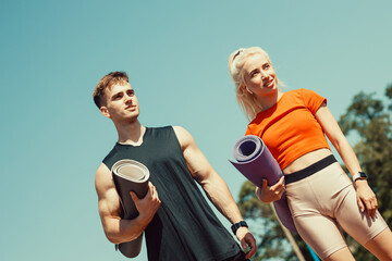 Fototapeta premium young couple walking down the street with sports mats in their hands