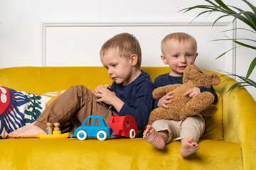 Two brothers sitting and playing cars together - blonde caucasian boys spending time at home