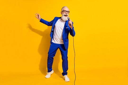 Full size photo of happy cheerful good mood mature businessman singing karaoke isolated on yellow color background