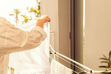 Woman check stains after washing. Female hanging her laundry on balcony on the drying rack opposite...