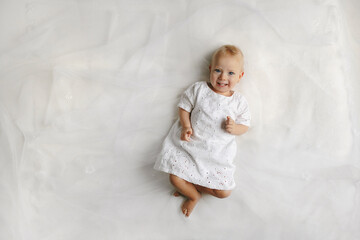 Fototapeta premium Top view on the female little baby lying on the bed. Concept of happy childhood.