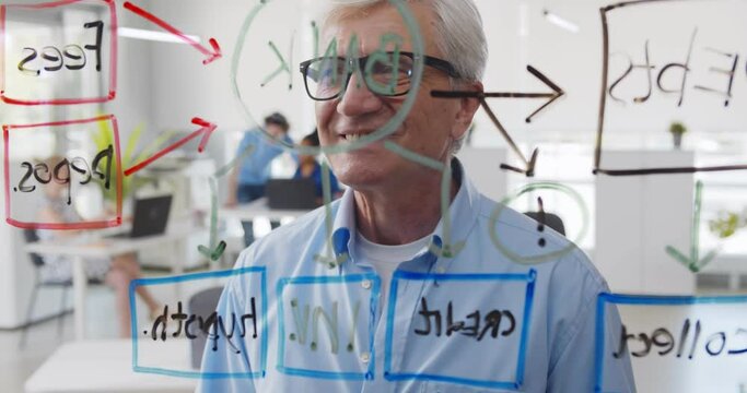 Mature businessman working in creative office reading notes on glass board