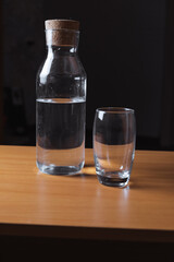 a closed bottle of water and an empty glass are on the table