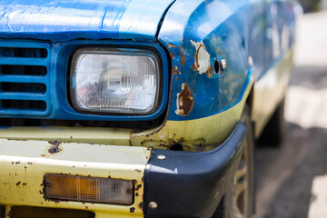 Headlight of an old rusty car with Traces of the cracked car's colors