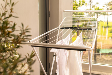 Hanging laundry on balcony on the drying rack opposite sea and palm trees view at sunset sunshine