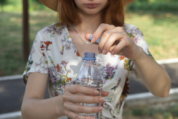 The girl opens a bottle of water. Pure drinking water in a plastic bottle. Opening bottle of water close-up