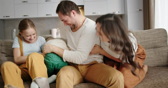 Happy family sitting at home on the couch in the kitchen smiling happy laughing tickling each other hugging loving parents and two children