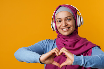 Middle eastern woman in hijab gesturing and using headphones