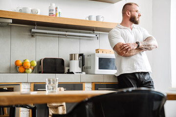 White man wearing eyeglasses looking aside while standing in kitchen