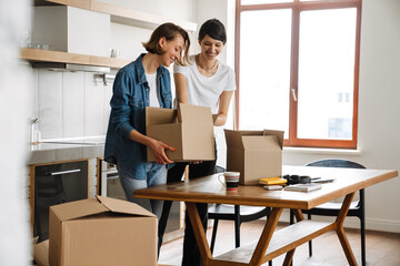 Fototapeta na wymiar A positive lesbian couple sorting boxes after moving