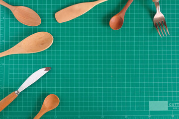 Kitchenware and wood spoon on cutting mat background.
