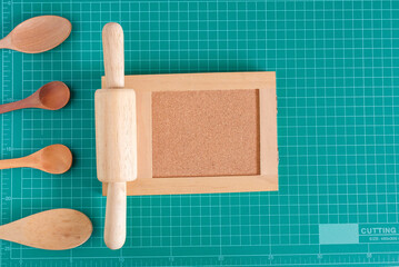 Kitchenware and wood spoon with wood board on cutting mat background.