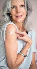 Reife Frau mit Pflaster am Oberarm nach Impfung