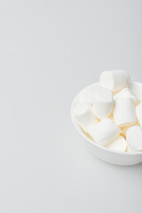 high angle view of soft and puffy marshmallows in bowl on white
