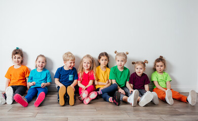 Cheerful children sitting on a floor near the wall