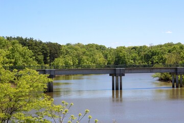 The footbridge over the lake at the park on a sunny day.