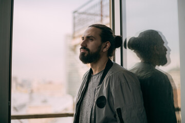 Portrait of a young handsome man at the window overlooking the city. City life.