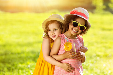 Portrait of a white and Black girl friends in a summer park. Friendly warm hugs of children
