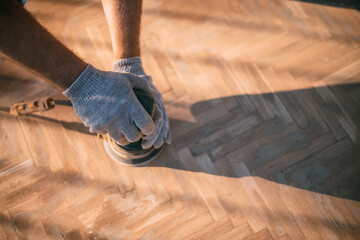 A male carpenter works with a wood grinder. Close-up. Professional equipment and protective...