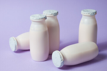 Bottles with probiotics and prebiotics dairy drink on light purple background.