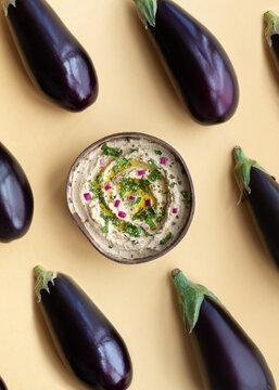 Bowl with Baba ghanoush dish on table with eggplants
