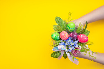 Easter bouquet. Decorative bouquet for Easter in the hands of a child. Children's hand holds a bouquet on a yellow background. Place for text