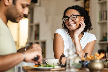 Middle eastern man and woman smiling while having breakfast at home